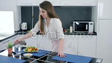 年轻女子在家做完沙拉<strong>后</strong>从<strong>厨</strong>房的桌子上打扫卫生